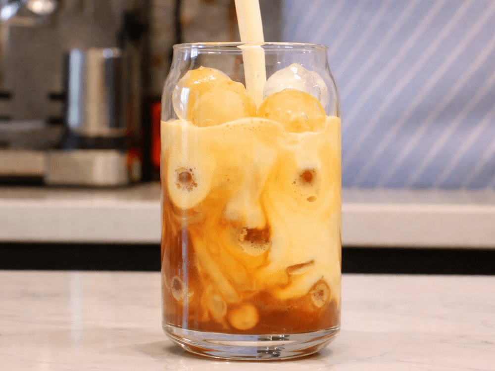 iced shaken espresso in a glass with milk being poured into it