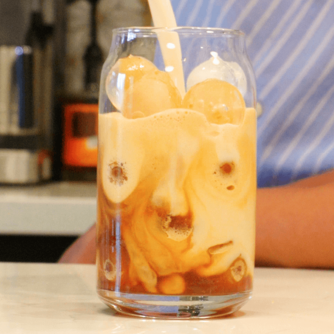 iced shaken espresso in a glass with milk being poured into it