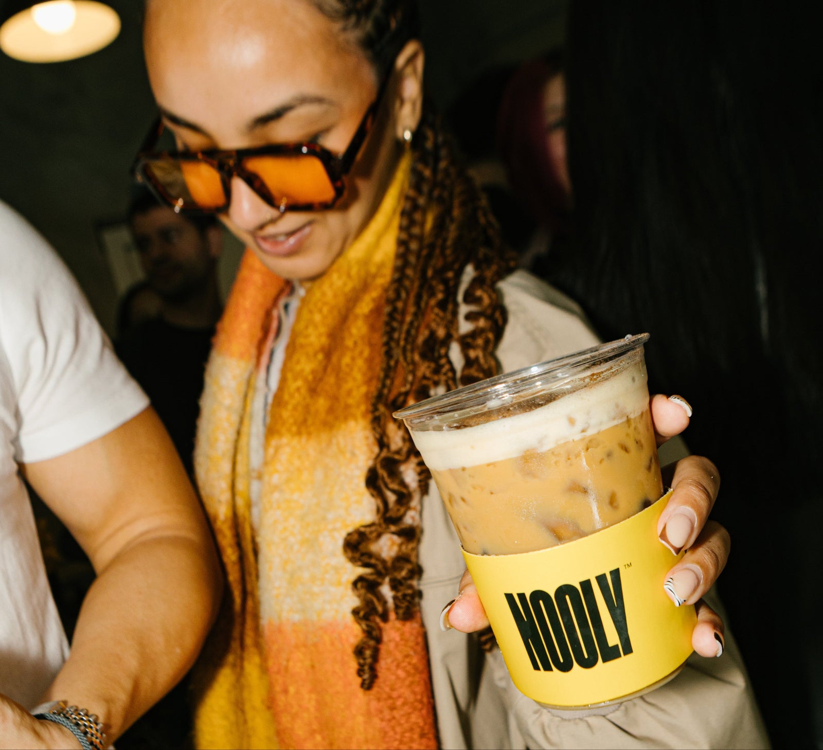 A barista pouring Nooly Almond Croissant syrup into an iced latte