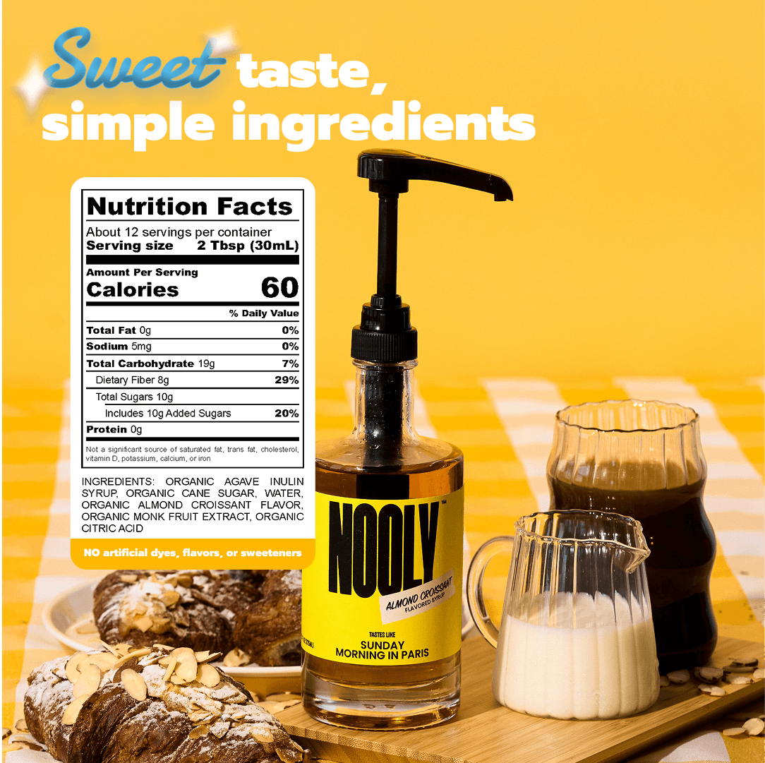 Bottle of NOOLY almond coffee syrup nutrition facts and almond syrup recipe with a glass of coffee, milk, and pastries on a yellow background
