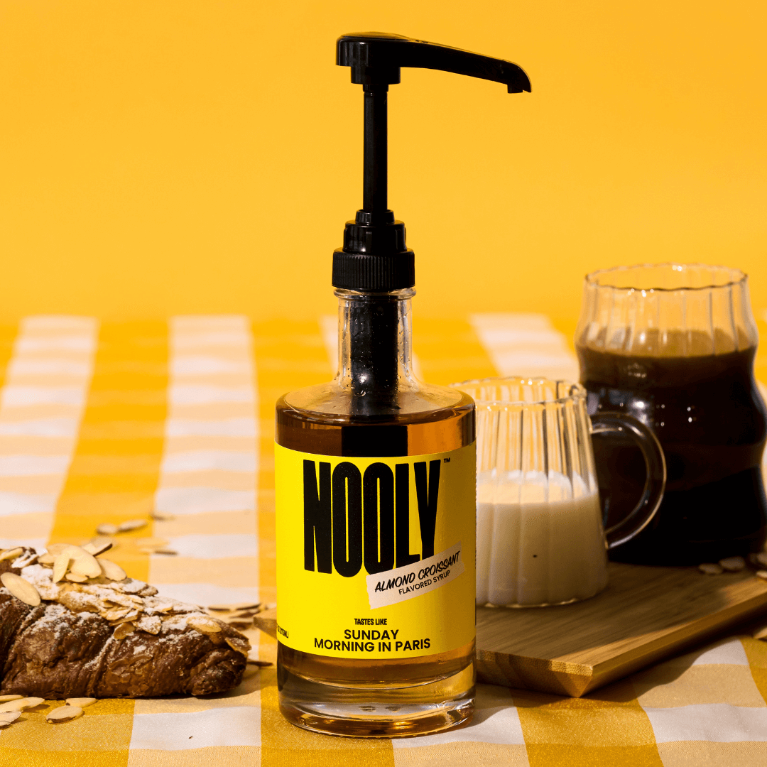 Bottle of Nooly almond coffee syrup with a syrup pump attached to the top