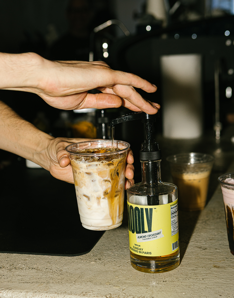 Person pouring coffee syrup in coffee